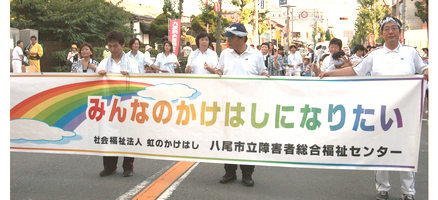 「みんなのかけはしになりたい」の横断幕を持ってパレード