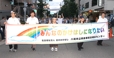 みんなのかけはしになりたいという垂れ幕を持って歩く様子